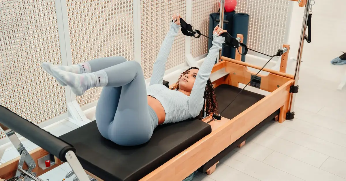 Woman exercising on a reformer machine focused on leg and core workouts