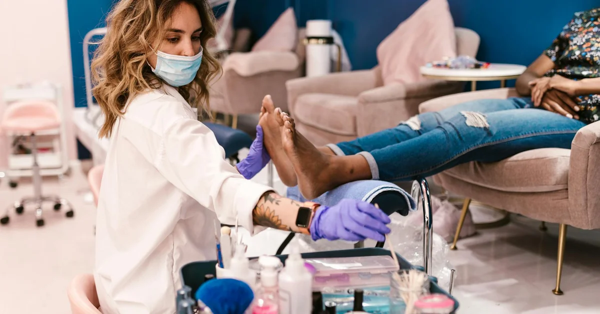 A foot care specialist provides treatment to a client's feet in a salon setting.