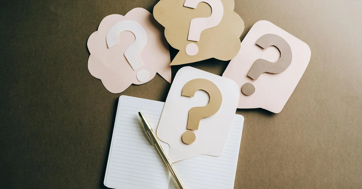 A notepad with a pen and speech bubbles featuring question marks.